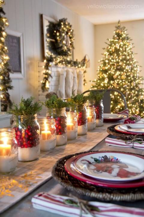 Cider pots with plants and candles in the center of the Christmas dinner table Photo by Pinterest
